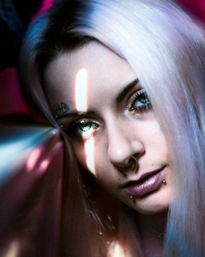 our-story-02 Artistic close-up of a woman with piercings and green eyes, featuring a dramatic light effect.